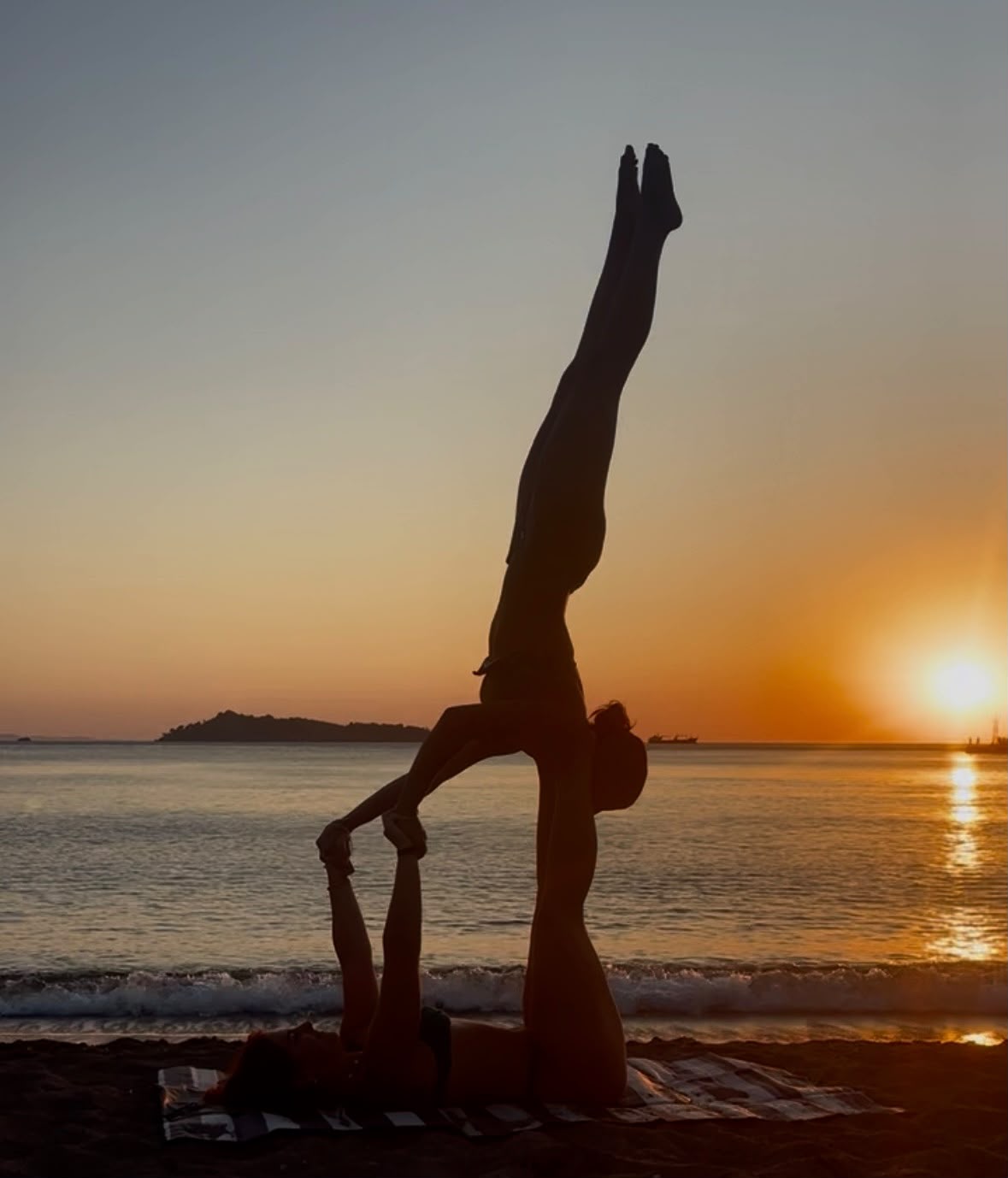 Acro yoga silhouette on the beach at sunset